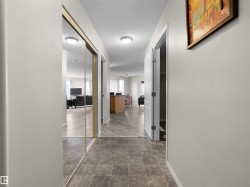 Hallway featuring square tile flooring, light neutral wall paint, and overhead flush-mount lighting - 