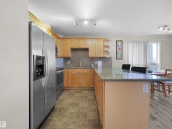 Kitchen featuring stainless steel appliances, light wood cabinetry, a tiled backsplash, and granite countertops - 