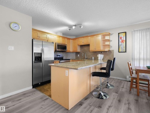 Kitchen featuring wood cabinetry, stainless steel appliances, a granite countertop island, and tile backsplash - 7123 7327 South Terwillegar Drive, Edmonton, AB - Indoor Photo Showing Kitchen
