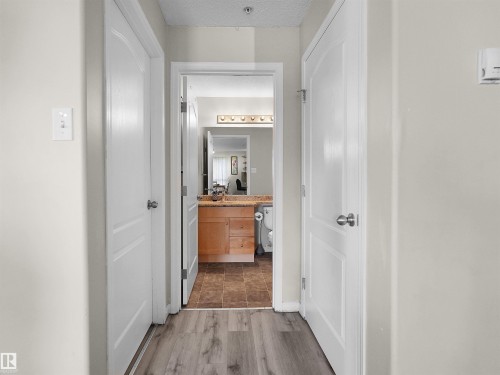 Hallway featuring wood-finish flooring, light grey wall paint, and white paneled doors - 7123 7327 South Terwillegar Drive, Edmonton, AB - Indoor Photo Showing Other Room