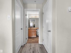Hallway featuring wood-finish flooring, light grey wall paint, and white paneled doors - 