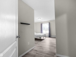 Spacious room featuring wood-finish flooring, a large window with natural light, neutral wall colors, and white trim - 