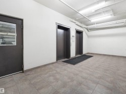 Tile flooring throughout the common area, featuring two elevators with brushed metal doors and a fire-rated door with a wired glass window - 