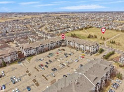 Multi-story residential buildings featuring balconies, surface parking areas, and surrounding green spaces - 