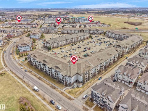 Expansive aerial view of a multi-unit residential complex featuring multiple buildings with private balconies and a large central parking area - 7123 7327 South Terwillegar Drive, Edmonton, AB - Outdoor With View