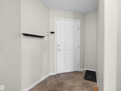 Entryway featuring a white paneled door, brown square tile flooring, light neutral wall paint, and white baseboards - 