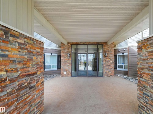 Covered entry featuring stacked stone accents and automatic glass doors - 7123 7327 South Terwillegar Drive, Edmonton, AB - Outdoor With Exterior