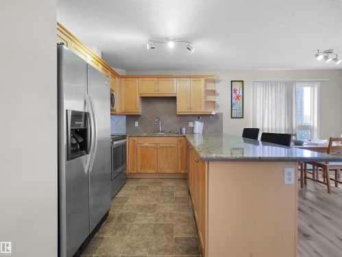 Kitchen featuring stainless steel appliances, light wood cabinetry, a tiled backsplash, and granite countertops - 7123 7327 South Terwillegar Drive, Edmonton, AB - Indoor Photo Showing Kitchen