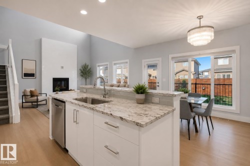 Kitchen island featuring a stainless steel sink and integrated dishwasher. Virtually Staged. - 635 42 Street, Edmonton, AB - Indoor