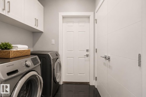 Laundry area featuring dark tile flooring and light gray wall paint. Virtually Staged.. Virtually Staged. - 635 42 Street, Edmonton, AB - Indoor Photo Showing Laundry Room