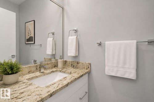 Vanity featuring a light-toned granite countertop with an undermount sink and a contemporary chrome faucet. Virtually Staged. - 635 42 Street, Edmonton, AB - Indoor Photo Showing Bathroom
