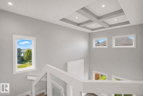 Staircase with modern glass railing and white newel posts, featuring a coffered ceiling with recessed lighting. Virtually Staged. - 635 42 Street, Edmonton, AB - Indoor Photo Showing Other Room