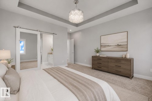 Spacious bedroom featuring a tray ceiling, recessed lighting, carpet flooring, and white barn doors. Virtually Staged. - 635 42 Street, Edmonton, AB - Indoor Photo Showing Bedroom