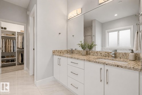 Dual vanity with stone countertops, integrated sinks, chrome fixtures, and a large mirror. Virtually Staged. - 635 42 Street, Edmonton, AB - Indoor Photo Showing Bathroom