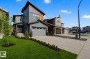 Contemporary multi-level residence featuring gray siding, a triple tandem garage, and a concrete driveway. Grass virtually enhanced to give a summer look. - 635 42 Street, Edmonton, AB  - Outdoor With Facade 