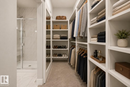 Expansive walk-in closet featuring extensive built-in shelving, hanging rods, and plush carpeting. Virtually Staged. - 635 42 Street, Edmonton, AB - Indoor With Storage