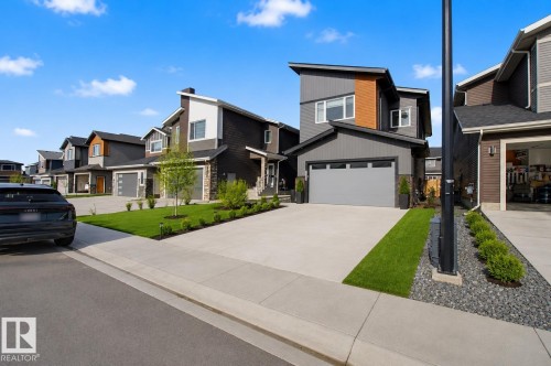 Contemporary exterior featuring mixed material siding, a flat roofline, an integrated garage, a concrete driveway, and established landscaping - 635 42 Street, Edmonton, AB - Outdoor With Facade