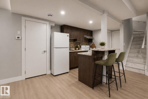 Compact kitchen area with wood-finish cabinetry and light-colored countertops. Virtually Staged. - 635 42 Street, Edmonton, AB - Indoor Photo Showing Kitchen