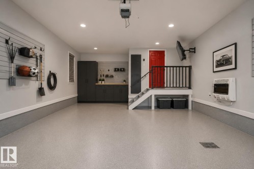 Spacious garage featuring epoxy flooring, built-in cabinetry, a utility sink, and wall-mounted storage systems. Virtually Staged. - 635 42 Street, Edmonton, AB - Indoor