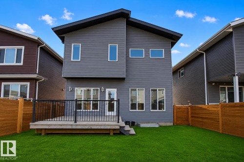 Modern exterior featuring horizontal gray siding and a black-trimmed roofline. Lawn enhanced for summer look. - 635 42 Street, Edmonton, AB - Outdoor With Deck Patio Veranda With Exterior