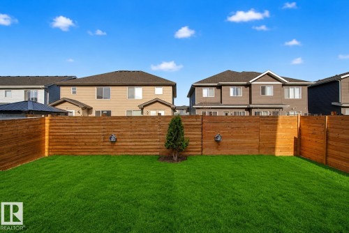 Private backyard featuring a well-maintained lawn and horizontal wood fencing. Lawn enhanced for summer look. - 635 42 Street, Edmonton, AB - Outdoor