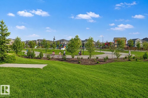 Expansive green space featuring manicured lawns, paved walking paths, and mature trees. Lawn enhanced for summer look. - 635 42 Street, Edmonton, AB - Outdoor