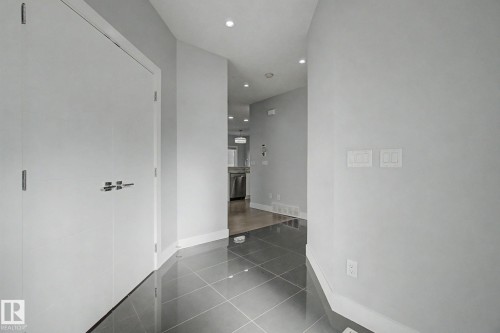 Entryway featuring large format grey tile flooring, white baseboards, recessed ceiling lighting, and two white bi-fold doors with contemporary hardware - 635 42 Street, Edmonton, AB - Indoor Photo Showing Other Room
