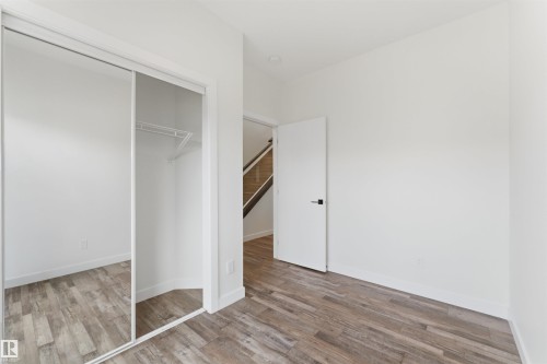 Room featuring wood-finish flooring, white walls, and a white interior door with black hardware - 12447 47 Street, Edmonton, AB - Indoor Photo Showing Other Room