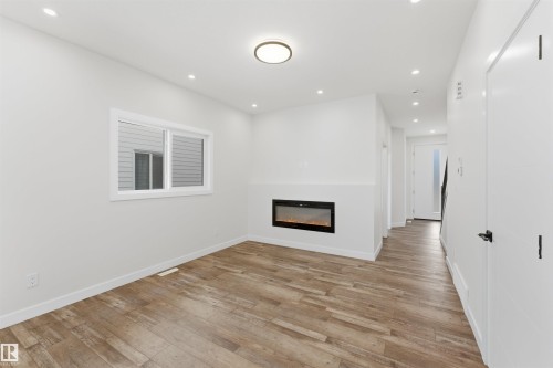 Inviting living area featuring a built-in electric fireplace, recessed lighting, and wood-finish flooring - 12447 47 Street, Edmonton, AB - Indoor With Fireplace