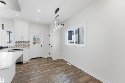 Bright interior space featuring wood-finish flooring, white walls, and a contemporary chandelier - 12447 47 Street, Edmonton, AB - Indoor Photo Showing Kitchen
