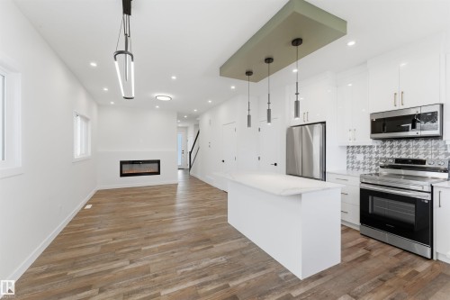 Open-concept living space featuring wood-finish flooring and recessed lighting - 12447 47 Street, Edmonton, AB - Indoor Photo Showing Kitchen With Upgraded Kitchen