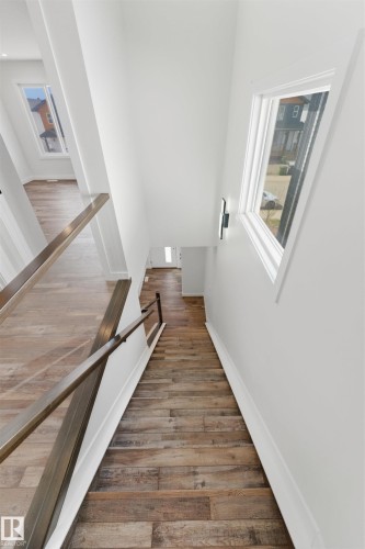 Staircase featuring wood-finish flooring, metal handrails, and a modern wall sconce - 12447 47 Street, Edmonton, AB - Indoor Photo Showing Other Room