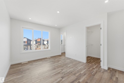 Spacious room featuring wood-finish flooring, recessed lighting, and a large multi-pane window - 12447 47 Street, Edmonton, AB - Indoor Photo Showing Other Room
