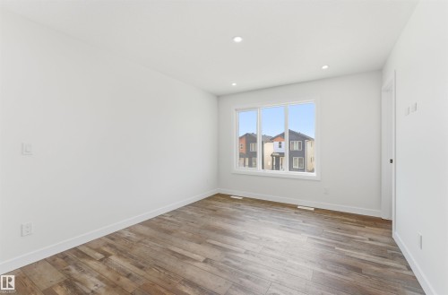 Spacious room featuring wood-finish flooring, recessed lighting, and a large window - 12447 47 Street, Edmonton, AB - Indoor Photo Showing Other Room