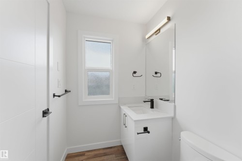 Bathroom featuring a white vanity with integrated sink, matte black faucet, and a large wall-mounted mirror - 12447 47 Street, Edmonton, AB - Indoor Photo Showing Bathroom