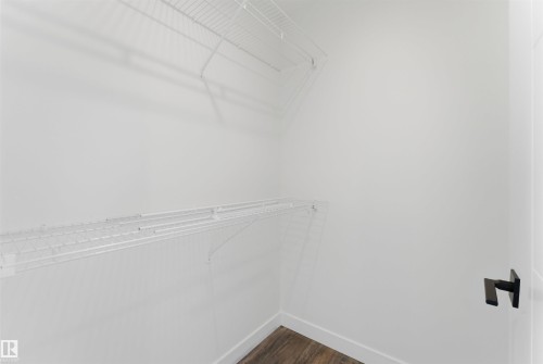 Walk-in closet featuring white wire shelving, white baseboards, and wood-finish flooring - 12447 47 Street, Edmonton, AB - Indoor With Storage