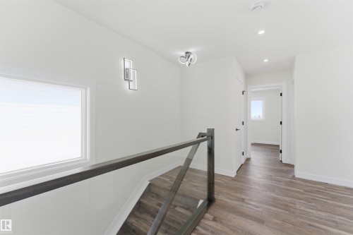 Upper-level hallway featuring wood-finish flooring, white walls, and contemporary light fixtures - 12447 47 Street, Edmonton, AB - Indoor Photo Showing Other Room