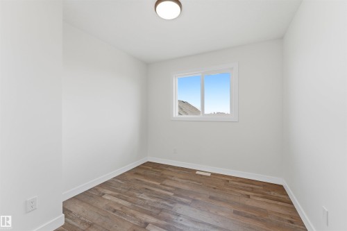 Bright interior room featuring wood-finish flooring, white baseboards, and a contemporary ceiling light fixture - 12447 47 Street, Edmonton, AB - Indoor Photo Showing Other Room