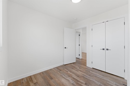 Open interior space featuring wood-finish flooring, white baseboards, and white walls - 12447 47 Street, Edmonton, AB - Indoor Photo Showing Other Room