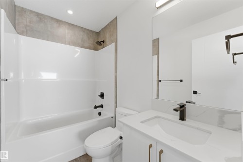 Full bathroom featuring a white vanity with a rectangular undermount sink, a stone-finish countertop, and a large wall-mounted mirror - 12447 47 Street, Edmonton, AB - Indoor Photo Showing Bathroom