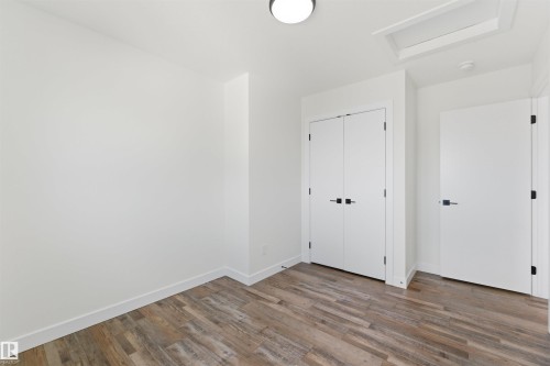 Interior room with wood-finish flooring, white walls, and bright overhead lighting - 12447 47 Street, Edmonton, AB - Indoor Photo Showing Other Room