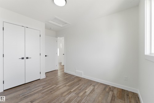 Wood-finish flooring throughout, bright white walls, and a recessed ceiling light - 12447 47 Street, Edmonton, AB - Indoor Photo Showing Other Room