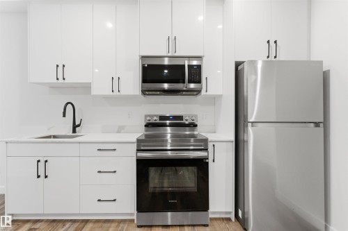 Contemporary kitchen featuring white cabinetry, stainless steel appliances, a matte black faucet, and light-toned countertops - 12447 47 Street, Edmonton, AB - Indoor Photo Showing Kitchen With Stainless Steel Kitchen With Upgraded Kitchen