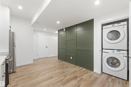 Utility space featuring stacked washer and dryer, wood-finish flooring, recessed lighting, and a decorative paneled accent wall - 12447 47 Street, Edmonton, AB - Indoor Photo Showing Laundry Room