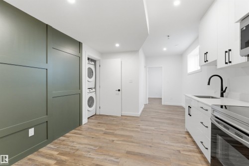 Contemporary kitchen area featuring white cabinetry, quartz-style countertops, and a black gooseneck faucet - 12447 47 Street, Edmonton, AB - Indoor Photo Showing Laundry Room