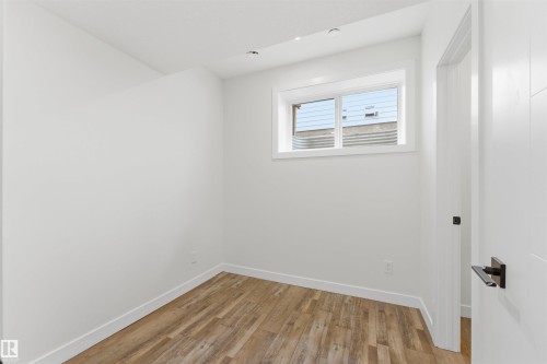 Room featuring wood-finish flooring, white walls, and a window with a white frame - 12447 47 Street, Edmonton, AB - Indoor Photo Showing Other Room