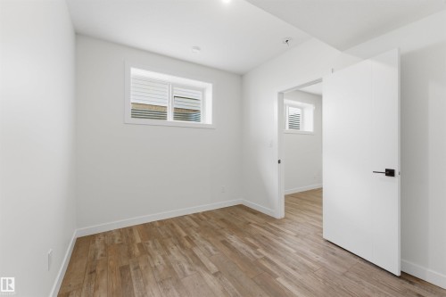 Room featuring wood-finish flooring, white walls, and a recessed window with horizontal blinds - 12447 47 Street, Edmonton, AB - Indoor Photo Showing Other Room