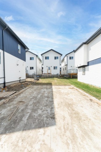 Backyard featuring a concrete pad, a partially grassed area, and a rear door with temporary steps - 12447 47 Street, Edmonton, AB - Outdoor With Exterior