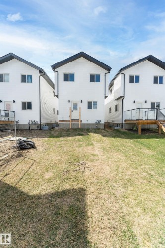Rear exterior featuring white horizontal siding, black trim, and a gabled roofline - 12447 47 Street, Edmonton, AB - Outdoor With Exterior