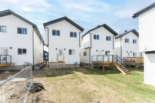 Rear exterior featuring white vinyl siding, black trim, and dark roofing - 12447 47 Street, Edmonton, AB - Outdoor With Exterior